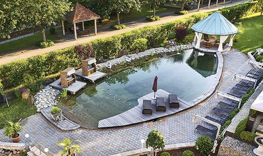 Naturaussenbecken mit Liegen an einem sonnigen Tag