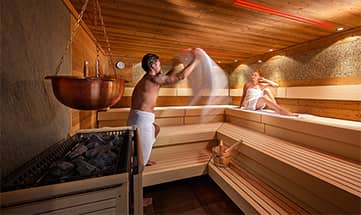 Paar erholt sich bei frischem Aufguss in der Kräutersauna