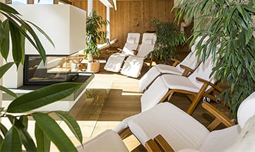 Ein Ruheraum mit weißen Liegen rund um einen Kamin