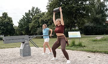Zwei Frauen machen draußen gemeinsam Krafttraining