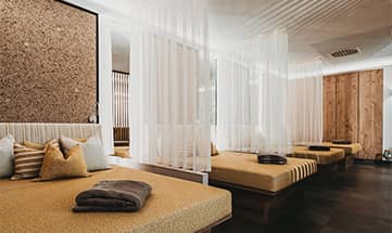 Beige farbige Betten und weiße Vorhänge im Ruheraum Wiesn