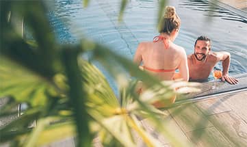 Paar am Beckenrand vom Outdoor Pool am hellichten Tag