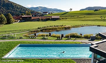 Frau schwimmt im Pool vor malerischer Berglandschaft