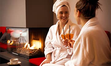 Zwei Freundinnen in weißen Bademänteln genießen Wellness