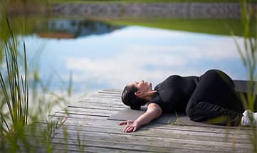 Frau macht Yoga am See