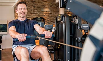 Mann rudert an einem Sporgerät