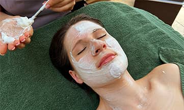 Frau erhält eine Kosmetikbehandlung mit Schaummaske