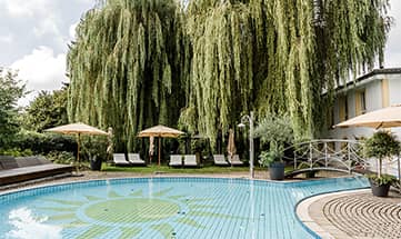 Der Außenpool am helllichten Tag neben großen Bäumen