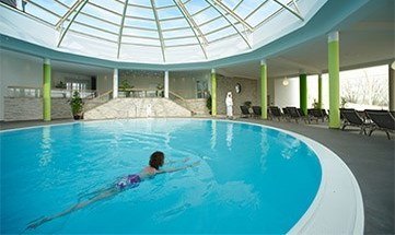 Frau schwimmt in Innenbecken unter runder Kuppel