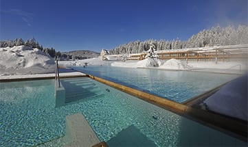 Außenpool im Winter mit verschneiter Landschaft