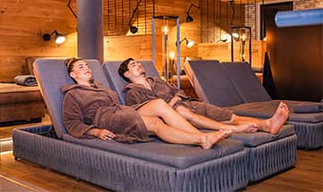 Paar erholt sich auf Liegen im Ruheraum  