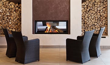 Vier schwarze Stühle vor einem Kamin