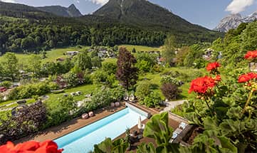 Blick von oben auf den Außenpool und die grüne Natur rund um den Pool