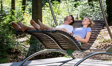 Mann und Frau entspannen gemeinsam auf Liege im WaldSpa