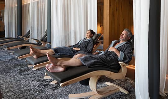 Paar entspannt auf schwarzen Liegen im Ruheraum