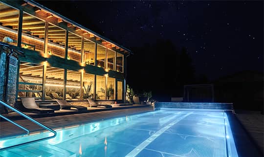 Blau beleuchteter Aussenpool am Abend mit Aussicht